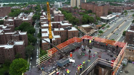 Vista-Aérea-Alrededor-De-Una-Grúa-Que-Levanta-Barras-De-Refuerzo-A-Los-Trabajadores-En-La-Parte-Superior-De-Un-Edificio-En-Nueva-York