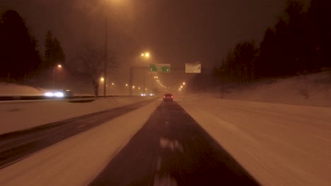 POV-Aufnahme-Hinter-Einem-Schwarzen-Auto-Auf-Einer-Verschneiten-Autobahn-In-Helsinki,-Finnland