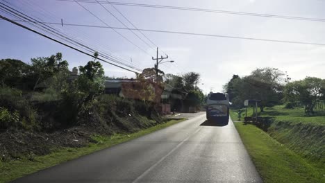 Driving-along-residential-road-with-bus,-car-and-motorcycle-traffic-with-electric-lines-above,-Windshield-front-view-shot