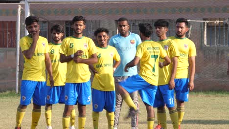 Equipo-De-Fútbol-Local-Con-Tops-Amarillos-Parados-Antes-De-Comenzar-En-Karachi,-Pakistán