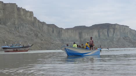 Young-Pakistani-Boy-Walking-Past-Carrying-Plastic-Petrol-Can-With-Fishing-Boat-In-Background-At-Gwadar