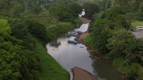 Pushing-tour-boat-loaded-with-passengers-into-river,-Aerial-dolly-in-lowering-shot