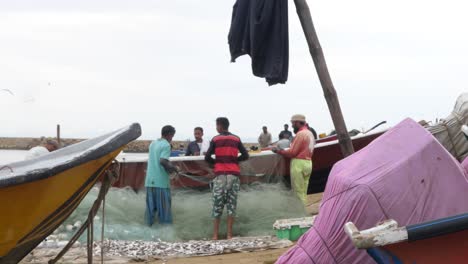 Pescador-Local-Clasificando-La-Red-De-Pesca-En-Gwadar-Junto-Al-Barco-En-Gwadar-En-La-Costa-De-Baluchistán