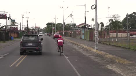 Hombre-Montando-En-Bicicleta-Superado-Por-Un-Camión-Suv-En-Un-área-De-Bajos-Ingresos-De-La-Ciudad,-Cámara-Lenta-Sigue-Detrás-De-La-Toma