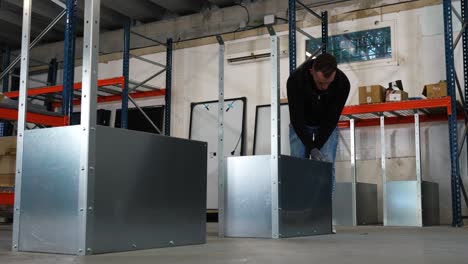 Slowmotion-rotating-shot-of-a-worker-assembling-metal-shelves-in-a-warehouse