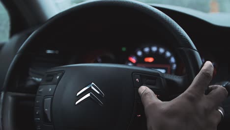 Driver-adjusting-controls-from-the-steering-wheel-of-Citroen-car-while-driving