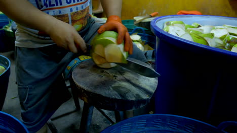 Hombre-Pelando-Coco-Con-Un-Cuchillo-Afilado-Y-Colocándolos-En-Agua-En-Un-Contenedor-Grande