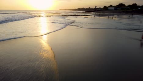 AERIAL:-Drone-shot-showing-the-waves-and-tourists-on-a-bali-beach