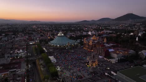 Luftaufnahme-Rund-Um-Die-Beleuchtete-Basilika-Von-Guadalupe,-Abenddämmerung-In-Mexiko---Kreisen,-Drohnenaufnahme