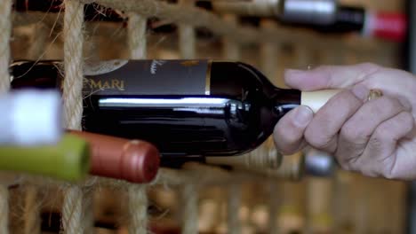 Close-up-of-man-carefully-taking-one-Due-Mary-red-wine-bottle-from-cellar-in-restaurant