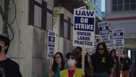 Un-Grupo-De-Trabajadores-Académicos-En-Ucla-Marcha-Con-Carteles-En-El-Campus