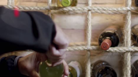 Man-holding-a-white-wine-glass-bottle-putting-it-back-into-wine-cellar