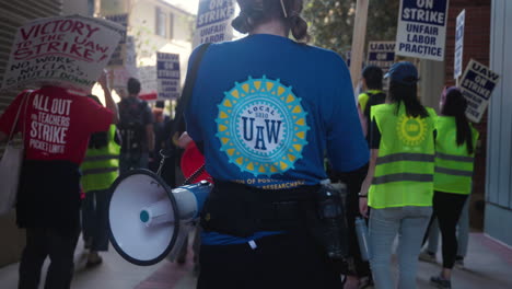 Eine-Junge-Frau,-Die-Ein-Uaw-5810-hemd-Trägt,-Marschiert-Beim-Uc-streik-Der-Akademischen-Arbeiter-An-Der-Ucla