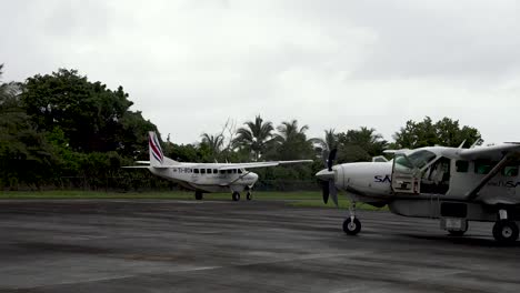 Cessna-208B-Grand-Caravan-EX-single-engine-plane-taking-off-from-rural-airport-with-another-parked-nearby,-Sansa-Airlines,-Follow-right-shot