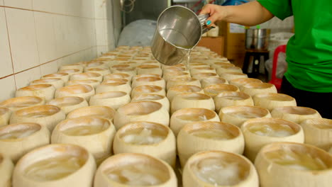 Unidentifiable-person-pouring-hot-coconut-water-jelly-into-empty-shell