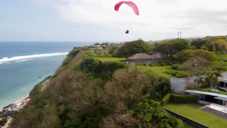 AERIAL:-Drone-shot-following-a-paraglider-above-a-beautiful-Bali-Beach