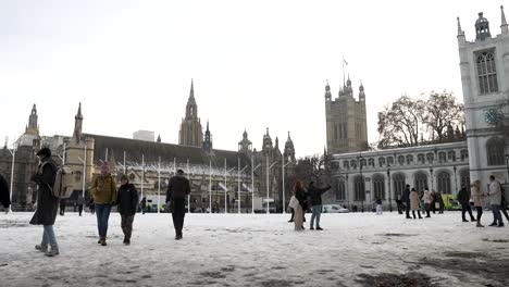 Gente-Caminando-Por-Los-Jardines-Cubiertos-De-Nieve-De-La-Plaza-Del-Parlamento-Con-El-Salón-De-Westminster-Y-La-Iglesia-De-Santa-Margarita-Al-Fondo