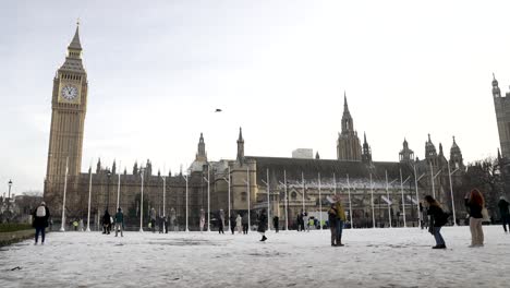 Turistas-Disfrutando-De-Los-Jardines-De-La-Plaza-Del-Parlamento-Cubiertos-De-Nieve-Con-El-Big-Ben-Y-Las-Casas-Del-Parlamento-En-El-Fondo