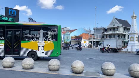 The-Trans-Jogja-city-bus-passes-the-Yogyakarta-monument-in-the-morning,-the-weather-is-clear-and-the-sky-is-blue