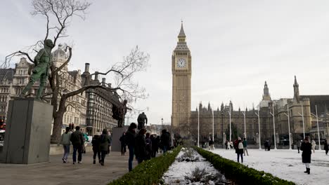 Leute,-Die-An-Der-Statue-Von-Jan-Christian-Smuts-Vorbeigehen,-Mit-Tauben,-Die-Auf-Schneebedeckten-Gärten-Des-Parliament-Square-Vorbeifliegen,-Und-Mit-Big-Ben-Im-Hintergrund