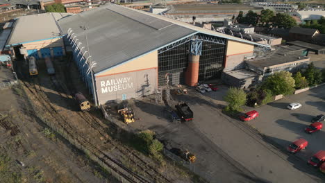 Pullback-Aerial-Drone-Shot-of-National-Railway-Museum-with-York-Station-and-River-Ouse-in-View-on-Sunny-Evening-Sunset---York-City-North-Yorkshire-United-Kingdom