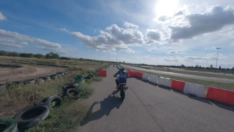 Fpv-Drohne-Kreist-Motorradfahrer-Ein,-Der-Die-Boxengasse-Hinunterfährt-Und-Sich-Der-Rennstrecke-Anschließt