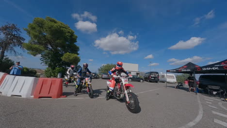 Fpv-Drone-Rodea-A-Un-Grupo-De-Motociclistas-Que-Salen-Del-Pozo-Y-Se-Unen-Al-Circuito-De-Carreras