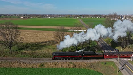 Drohne,-Die-Parallele-Ansicht-Eines-Dampfpersonenzuges-Fährt,-Der-An-Einem-Sonnigen-Herbsttag-Viel-Rauch-Und-Dampf-Bläst