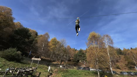 La-Niña-Se-Divierte-Con-La-Tirolesa-En-El-Parque-De-Aventuras-De-Cuerdas,-El-Bosque-En-El-Fondo-Y-El-Cielo-Para-Copiar-El-Espacio