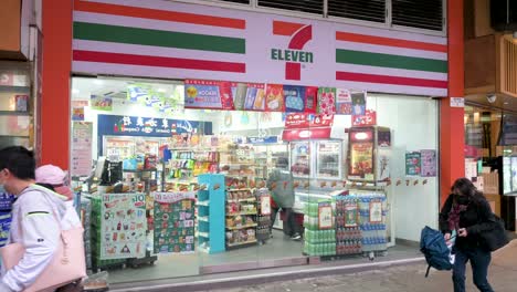 Los-Peatones-Pasan-Frente-A-La-Cadena-Multinacional-Estadounidense-De-Tiendas-De-Conveniencia,-7-eleven-En-Hong-Kong