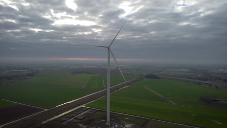 Turbina-Eólica-Con-Clima-Nublado-En-Los-Países-Bajos,-Junto-Con-Vías-De-Tren-En-El-Fondo