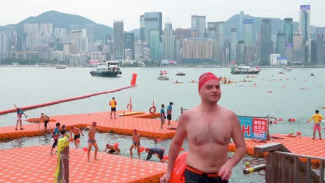 Los-Participantes-Cruzan-La-Línea-De-Meta-Durante-La-Competencia-Anual-De-Natación-New-World-Harbour-Race-Mientras-El-Horizonte-De-Hong-Kong-Se-Ve-En-El-Fondo.