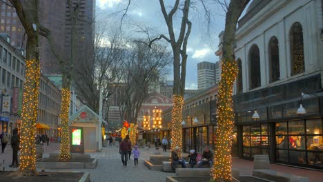 Gente-Paseando-Por-La-Calle-Con-árboles-Envueltos-En-Luces-Navideñas-En-Quincy-Market,-Boston,-Massachusetts