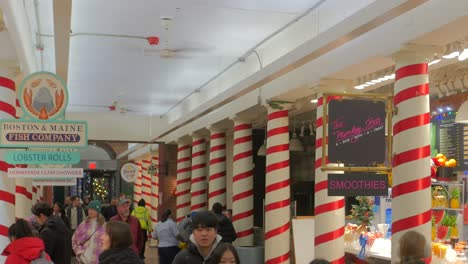 Innensäulen,-Die-Während-Der-Weihnachtszeit-Auf-Dem-Quincy-Market-In-Boston,-Massachusetts,-Mit-Einer-Menge-Von-Käufern-Mit-Roten-Bändern-Geschmückt-Sind