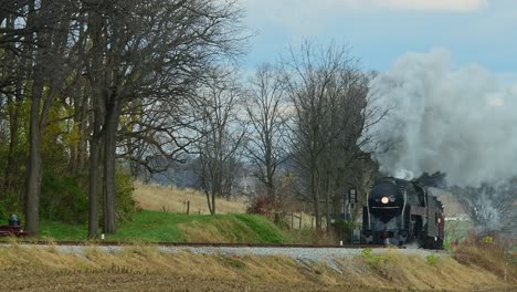 Una-Vista-De-Un-Tren-De-Pasajeros-De-Vapor-Que-Se-Acerca-Desde-Una-Larga-Distancia-En-Un-Frío-Día-De-Otoño-Con-Mucho-Humo