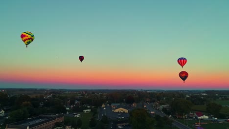 Una-Vista-Aérea-De-Varios-Globos-Aerostáticos-Flotando-En-El-Cielo-Durante-Un-Festival-Con-Multitudes-Observando,-En-Un-Día-De-Verano