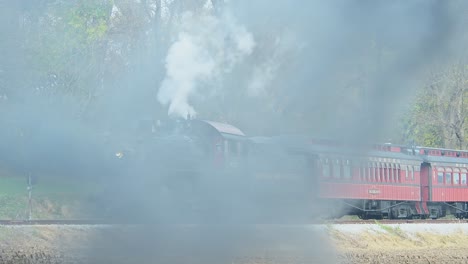 A-View-of-a-Steam-Passenger-Train-Stopped-on-a-Cold-Fall-Day-With-Lots-of-Smoke-and-Steam