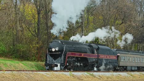 Una-Vista-De-Un-Tren-De-Pasajeros-De-Vapor-Que-Se-Acerca-Desde-La-Distancia-En-Un-Frío-Día-De-Otoño-Con-Mucho-Humo