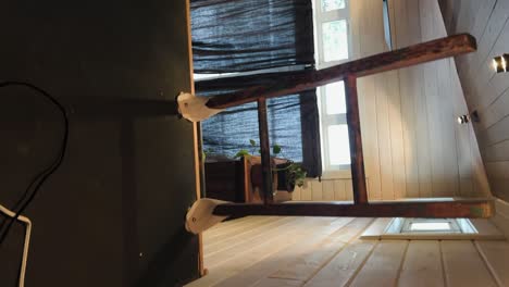 Vertical-video-of-somebody-waking-up-in-a-rental-home-loft-and-looking-out-of-a-window-next-to-them-revealing-a-snowy-pine-forest