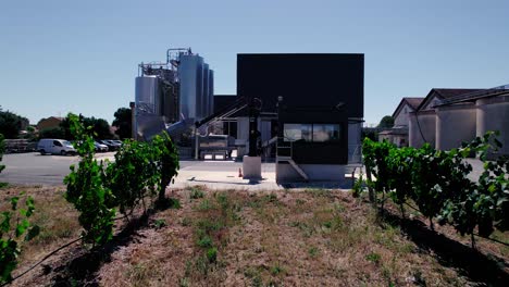 Aerial-view:-flying-through-the-field-of-grapes-towards-a-concrete-plant-in-Nimes,-France