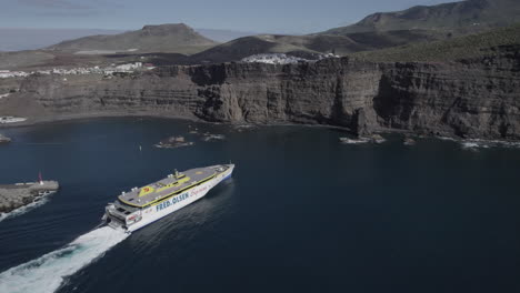 Aerial-shot-of-a-ferry-very-close-to-the-port-of-Agaete-and-maneuvering-to-dock