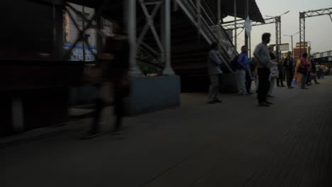 Low-angle-shot-of-local-train-entering-at-railway-station-platform-and-crowd-waiting-for-train-to-stop