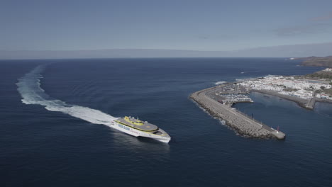 Toma-Aérea-Sobre-El-Ferry-Que-Llega-Al-Puerto-De-Agaete-En-Un-Día-Soleado