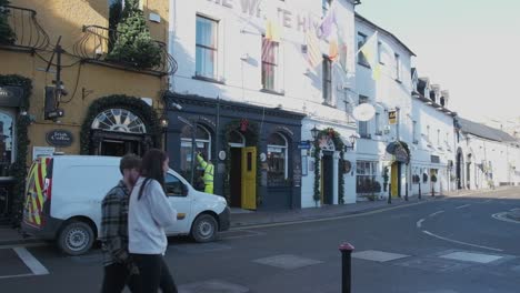 Trabajador-Del-Consejo-Del-Condado-Arreglando-Un-Poste-De-Luz-Después-De-Un-Accidente-Y-Una-Pareja-Caminando-En-Un-Soleado-Día-De-Invierno-En-Kinsale,-Irlanda