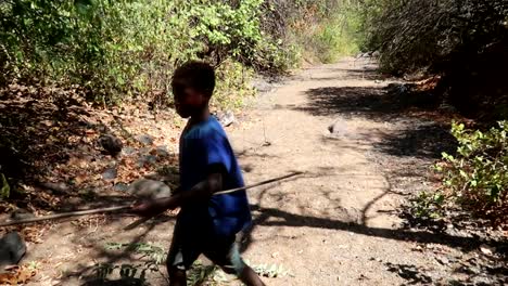 Niño-De-La-Tribu-Hadzabe-Cortando-Una-Rama-Con-Un-Cuchillo-Para-Hacer-Flechas-Y-Otras-Armas-En-Cámara-Lenta