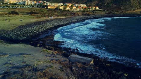 Paar-Steht-Auf-Felsigem-Hügel-Und-Hochzeitszeremonie-Am-Kiesstrand-Im-Hintergrund,-Teneriffa