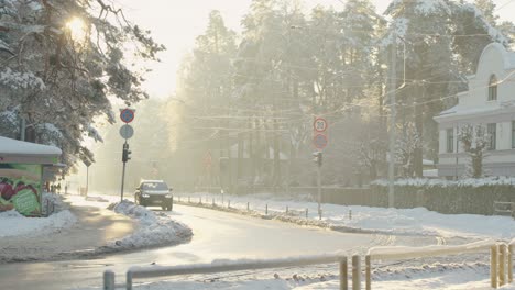 Slow-motion-establish-shot-of-car-passing-by-in-snowy-street-after-snowfall