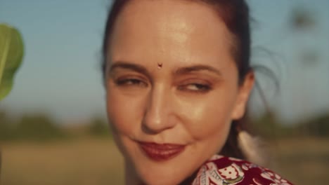 Up-close-face-of-a-woman-with-flawless-moisturized-skin-and-minimal-makeup-holding-a-leaf-in-her-hand