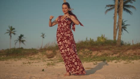 Woman-taking-deep-breaths-as-she-meditates-while-standing-at-the-beach-in-a-dress-with-trees-behind-her