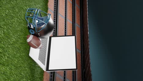 Ball-for-American-football,-american-football-helement-and-laptop-on-stadium-and-green-grass-background-with-copy-space